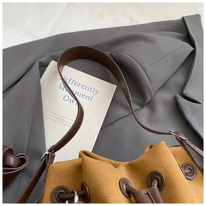 Close-up of mustard suede bucket bag with drawstring closure and silver hardware details