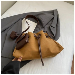 Detail of camel suede bucket bag with leather strap and detachable coin purse on white linen