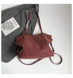 Detail of burgundy tote bag with subtle leopard print and adjustable strap in a lifestyle set