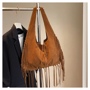 Detail of brown suede tote bag featuring long fringes and soft bohemian textures
