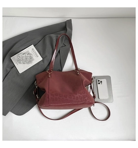 Macro view of burgundy leopard print tote showing suede texture and golden metal hardware