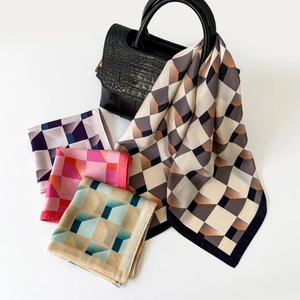 Modern geometric silk-like square scarf tied to a black leather bag in a minimalist style