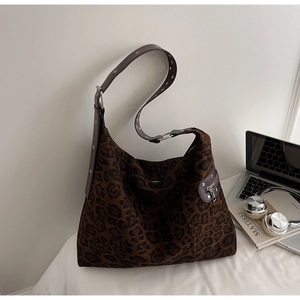 Detail of hobo bag featuring leopard print fabric and eyelet studded leather strap