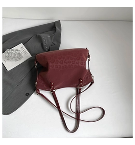 Macro detail of wine red leopard print tote bag with silver hardware on a white background