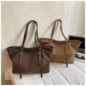 Close-up of brown and tan tote bags with decorative buckles and metal eyelet details