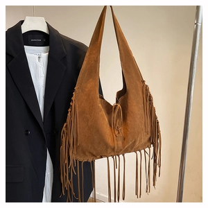 Macro detail of brown faux suede tote bag featuring long fringes and bohemian style