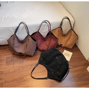 Vue à plat de quatre sacs cabas en daim marron, bordeaux, camel et noir avec glands