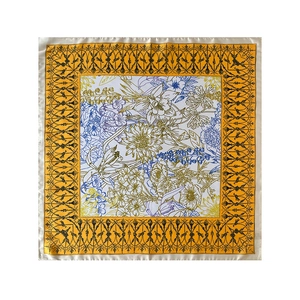 Detailed flat lay of a square silk scarf with blue and yellow floral prints and gold borders