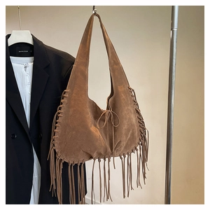 Detailed view of bohemian brown suede tote bag with fringe accents and braided rope edge