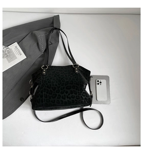 Detail view of black leopard print suede tote bag with golden hardware and accessories