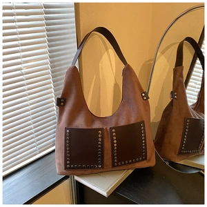 Detailansicht der braunen Wildledertasche mit Nieten und Fronttaschen bei sanftem Licht