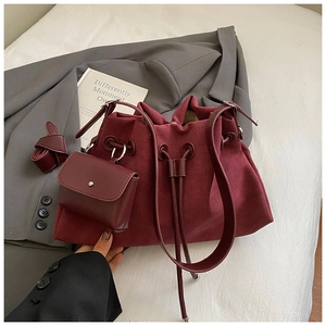 Detail view of burgundy faux suede bucket bag with drawstring closure and small pouch