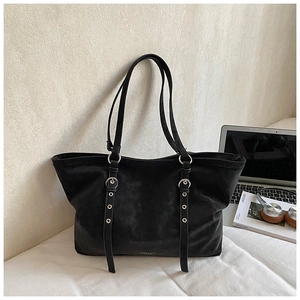 Close-up of a black matte leather tote bag with stylish metal ring decorative straps