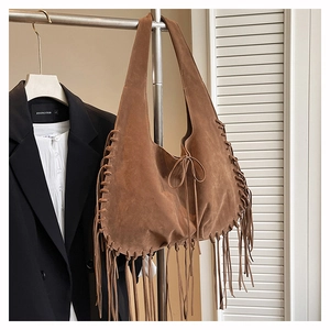 Detail of a brown suede tote bag with long fringes and bohemian bow tie decoration