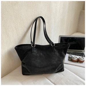 Detail of black suede tote bag with silver metal rings and spacious interior design