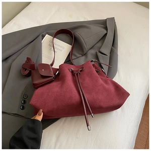 Detail of burgundy suede bucket bag with drawstring closure and matching small pouch