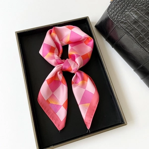Detailed view of knotted silk scarf with pink and orange geometric patterns on black bag