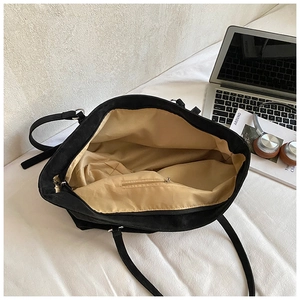 Interior view of large black tote bag showing a laptop, zip pocket and tan lining