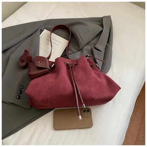 Detail of burgundy suede bucket bag with drawstring closure and matching coin purse