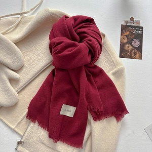 Detail of burgundy tassel scarf with herringbone texture and classic rectangular label
