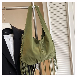 Detail of green suede hobo bag with long tassels and woven drawstring elements