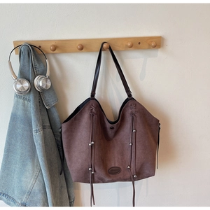 Vue détaillée du sac cabas en daim marron foncé avec des franges et des perles en métal