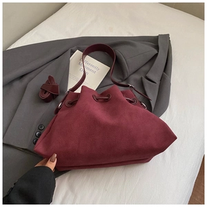 Detail of wine red suede bucket bag with drawstring closure and extra shoulder strap