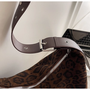 Detail of leopard print suede tote with leather strap and silver metal buckle adjustment