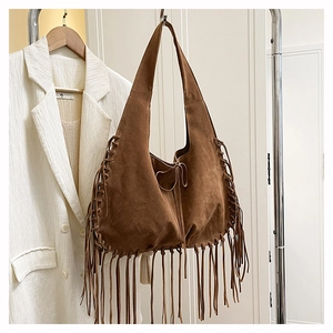 Detail of bohemian brown suede tote bag with long fringes hanging on a rack