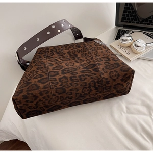 Detail of leopard print tote bag with brown leather strap and silver metal eyelets