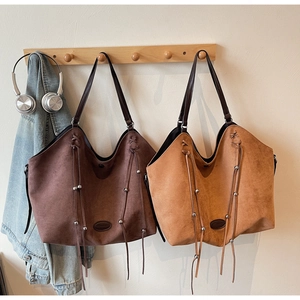 Détail de sacs cabas hobo avec cordon à pompons et texture en cuir mat marron