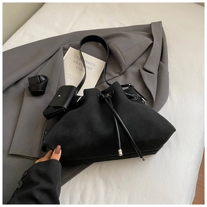 Detail of black drawstring bucket bag with small square pouch and suede texture