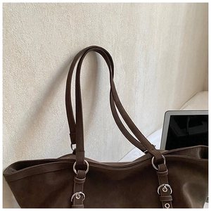 Detail of dark brown matte tote bag featuring silver metal rings and textured faux suede