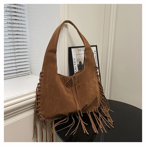 Detail of bohemian brown suede tote bag featuring long fringes and woven edge craftsmanship