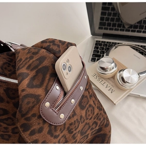 Detailed close-up of leopard print velvet bag with silver studs and functional zip pocket
