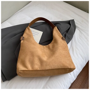 Detail einer Vintage Hobo-Tasche aus braunem Wildleder mit Lederriemen auf Sakko