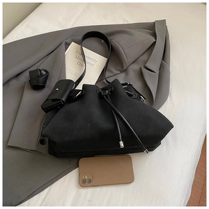 Macro shot of black suede drawstring bucket bag with mini pouch and phone size reference