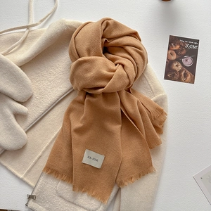 Close-up of camel knit scarf with tassel fringe on white fleece jacket for winter style