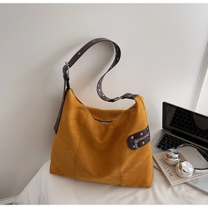 Close-up of yellow suede tote bag with brown leather strap and metallic eyelet details