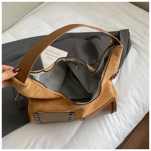 Detailaufnahme der braunen Wildledertasche mit Metallnieten und Fischgrätenfutter
