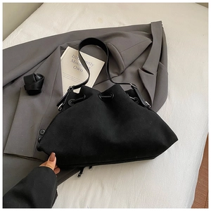 Detail of matte black bucket bag with drawstring closure and silver metal ring hardware