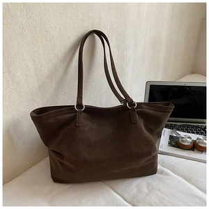 Detail view of large dark brown suede tote bag with slim shoulder straps and metal rings