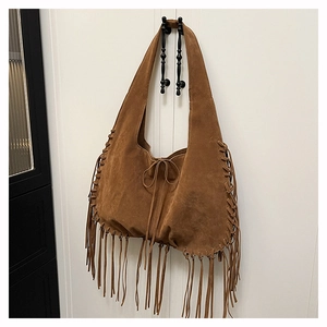 Close-up of brown suede hobo bag featuring decorative long fringe and woven details