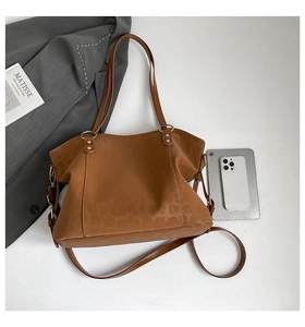Close-up of brown leopard print tote bag featuring metallic rivets and long shoulder strap