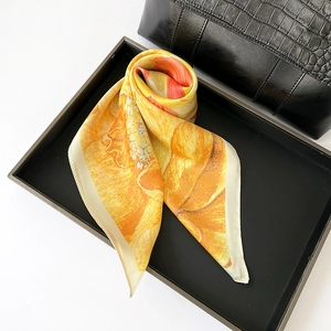 Detailed macro view showing the glossy sunflower floral print on a silky square scarf