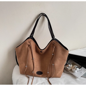 Détail du sac cabas en daim marron avec cordons en cuir et perles argentées pour le bureau