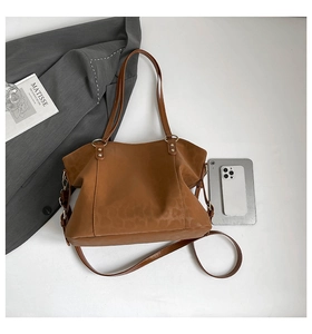 Macro shot of brown faux leather tote bag with subtle leopard texture and adjustable strap