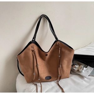 Détail du sac cabas en daim marron avec anses en cuir et pompons à perles argentées