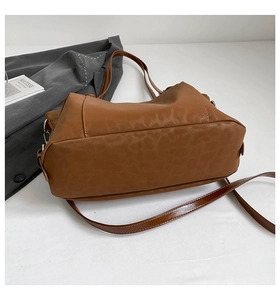 Detail view of large brown PU leather tote bag with fine stitching and metal buckle accents
