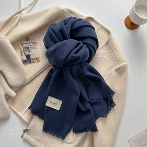 Detail of dark blue knit scarf with herringbone weave pattern and fringe tassels